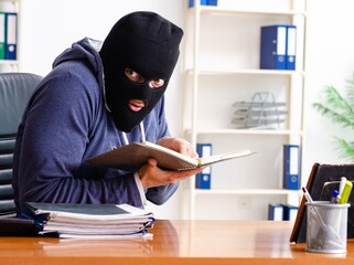 Male thief in balaclava in the office