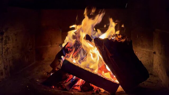 Slow motion 4K video of burning dry woods in the brick outdoor country house mantel at the cold autumn late evening. Home coziness and energy saving concept footage.