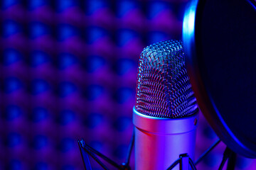Professional studio microphone against acoustic foam panel background in neon light