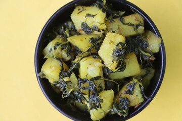 Aloo Palak sabzi, Spinach Potatoes dry curry served in a black bowl, Indian food