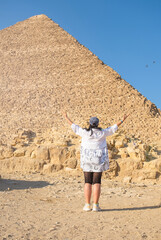 Woman wearing light clothing, facing the Pyramids of Gyza