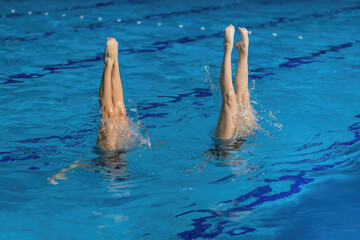 Aquatic poetry of a synchronized swimming duet, crafting a mesmerizing dance in the shimmering pool...
