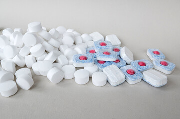 Chemical tablets for the dishwasher are scattered on the table. Colored capsules are dishwasher safe