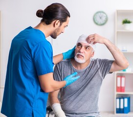 Young male doctor and old patient in first aid concept