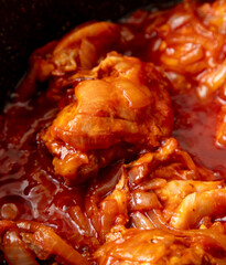 Chicken meat is stewed in tomato in a frying pan