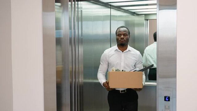 Dismissed african worker with dismissal box coming out of lift