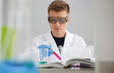 A male chemist holds test tube of glass in his hand overflows a liquid solution of potassium...