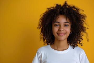 A young girl with curly hair standing in front of a vibrant yellow wall. Suitable for various purposes