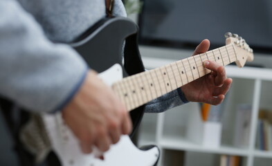 Male hands at home play and tune the electric guitar is engaged in music realizes listening enjoying music notation large concept closeup