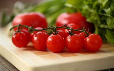 Cherry tomatoes lie on a cutting board in kitchen against backdrop of greenery healthy eating concept