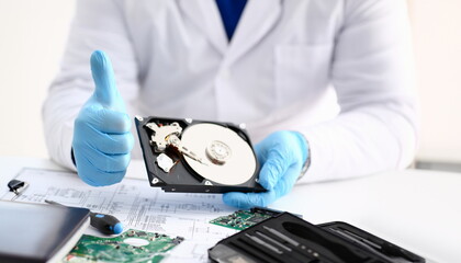 Male repairman wearing blue gloves is holding hard drive from computer laptop in hands show OK...