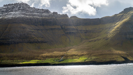 On the Faroe Islands, a small village nestles in the embrace of a dramatic landscape. Cliffs rise...
