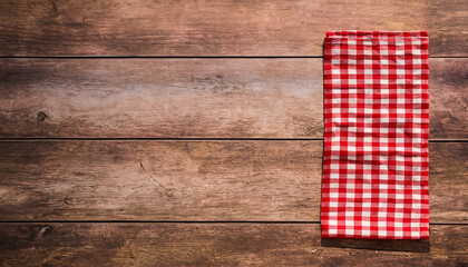 Obraz premium Red checkered napkin on a rustic wooden table with copy space for placing your text or product. Italian, homemade, traditional kitchen. High quality photo