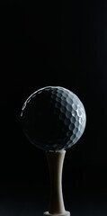 photo of a golf ball on a tee and against a dark background