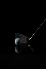 photo of a golf stick with the focus set on the golf ball in front of the stick and with a dark background