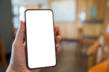 Person holding mobile phone with white empty blank screen on blurred office room background. Smartphone display mockup with blank white screen for mobile App Advertisement, Social media content.