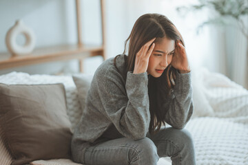 Depressed young woman sitting on couch in the living room at home, Frustrated confused female feels unhappy problem in personal life quarrel break up with boyfriend - obrazy, fototapety, plakaty