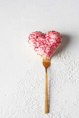 A heart-shaped doughnut with pink icing and red sprinkles on a golden fork, Happy valentine day...