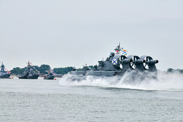 Hovercraft warship armed with armament sails into sea toward military target to attack and destroy