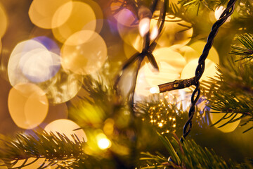 New year christmas tree branch with yellow flickering lights of garlands copy space background