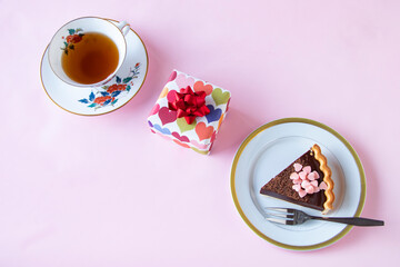 バレンタインのお菓子　手作りチョコレート・タルトと贈り物と紅茶（ペールピンクの背景）