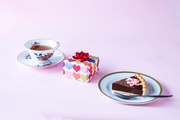 バレンタインのお菓子　手作りチョコレート・タルトと贈り物と紅茶（ペールピンクの背景）