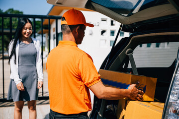 Naklejka premium Emphasizing efficient home delivery service a courier in uniform hands a cardboard parcel to a smiling woman customer at her front house door highlighting modern delivery logistics.