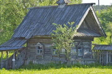 An old faded village house. A very old but intact European wooden house with a wooden roof. Summer day evening. 