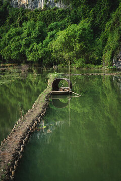 Traditional wooden boat in river along green grown lush karst mountains, Ninh Binh, Vietnam