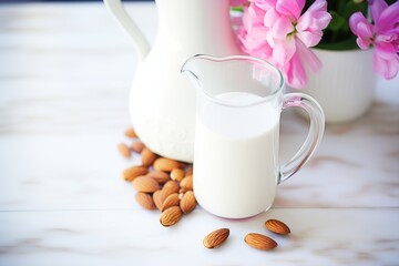 almond milk in a clear pitcher with whole almonds arranged around