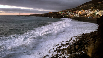 dramatic waves crashing against the shore at Puerto Naos on the beautiful Canary Island of La Palma, Spain, under a moody sunset sky