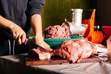 Crop woman cutting raw meat in kitchen