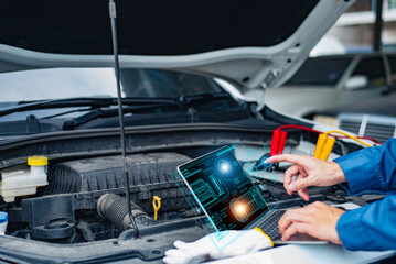 Mechanic with tablet analyzing car engine through diagnostic software with holographic display..