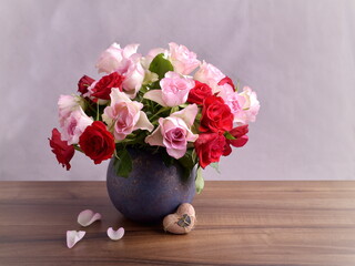 Bouquet of red and pink roses on wooden table. Heart and petals. Valentines day and mothers day card.