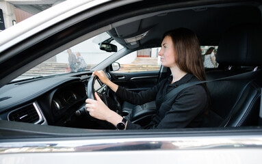 Woman in black clothes driving luxurious car