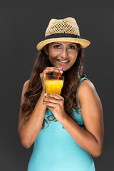 Indian woman drinking dark grey juice on colorful background