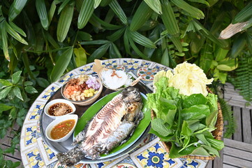 Grilled fish with Thai spicies salad , in Thai cal "Miang Pla Pao" on the table , top view Thai food.