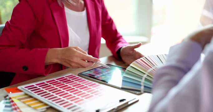 Man and woman discuss new paint colors comparing shades on set of color cards in store. Choosing color from color palette