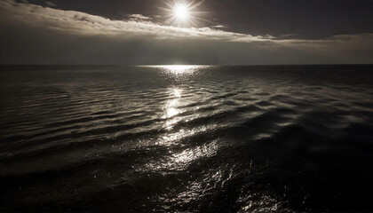 Undulating surface of the ocean with sun reflecting on the surface, horizon and sky