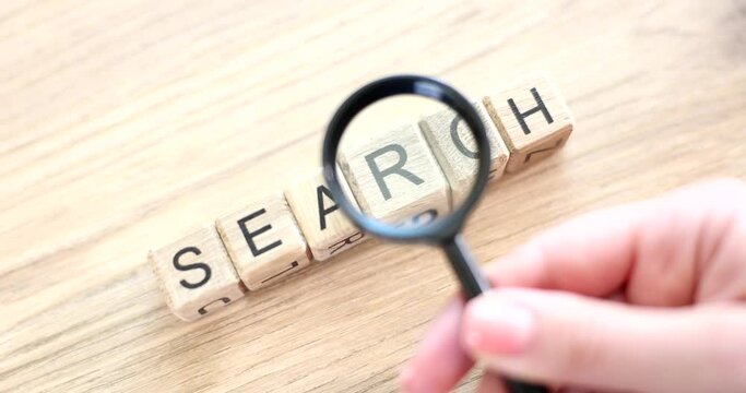 Magnifying glass and search word written on cube on wooden background. Glossary and interpretation