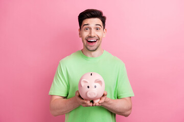 Photo of surprised funny young positive man hold piggy bank save money for dream purchase in his...