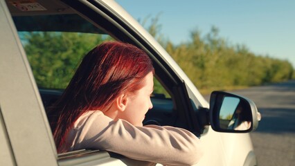girl rides car with her hand out window, conceptual car journey along road, outdoor entertainment, beautiful young woman smiling sunset, traveling by car camper, hand movements from window sunset