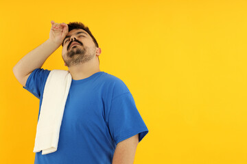 A fat man is tired after training, on a yellow background.