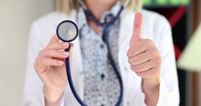 Doctor with thumb up gesture is holding stethoscope. Trust in concept of medical professional competence insurance and treatment
