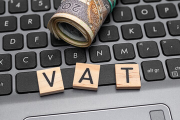 Napis VAT obok polskich pieniędzy na klawiaturze laptopa, podatek od towarów i usług  - obrazy, fototapety, plakaty