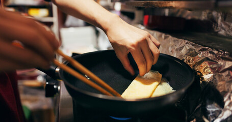 Cooking, chopsticks and person with egg in pan at market for frying food for meal preparation, eating and nutrition. Culinary, flame and closeup of chef prepare lunch, cuisine dinner and supper - obrazy, fototapety, plakaty