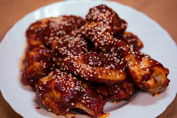Delicious fried chicken wings in buffalo sauce with sesame seeds. Fast junk food