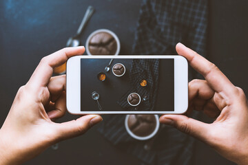Hand photographing homemade souffles and coffee on blackboard table top