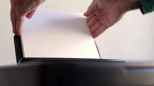 male hands putting A4 paper into a laser printer close-up. High quality 4k footage