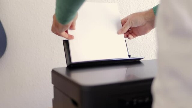 a man puts white paper into the printer, Laser printer in operation. Close-up of printing on paper. High quality 4k footage